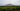 Field of maize growing in the desert with mountains starting to rise up in the background.